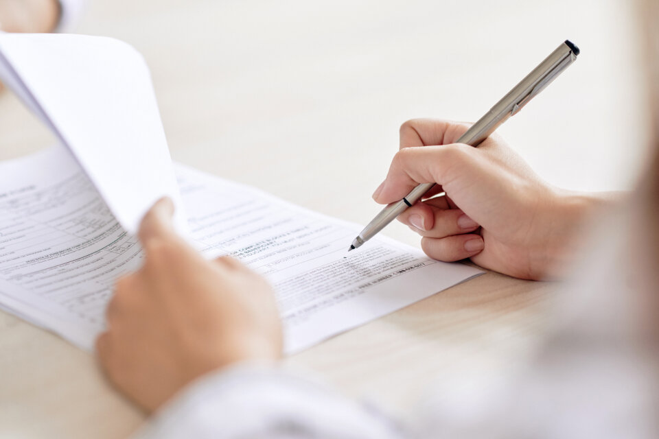 Eine Hand füllt ein Formular aus – symbolisch für den Tätigkeitsbericht der Schwerbehindertenvertretung und deren dokumentierte Arbeit im Unternehmen.
